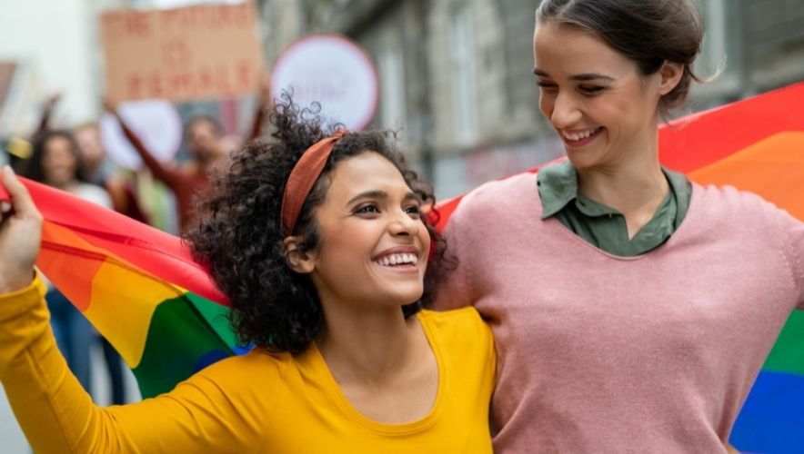 How to Celebrate Pride at Work - two women laughing while on a Pride march
