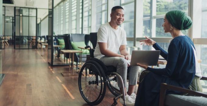 Disability recruitment - Man in wheelchair speaking with seated woman in head scarf